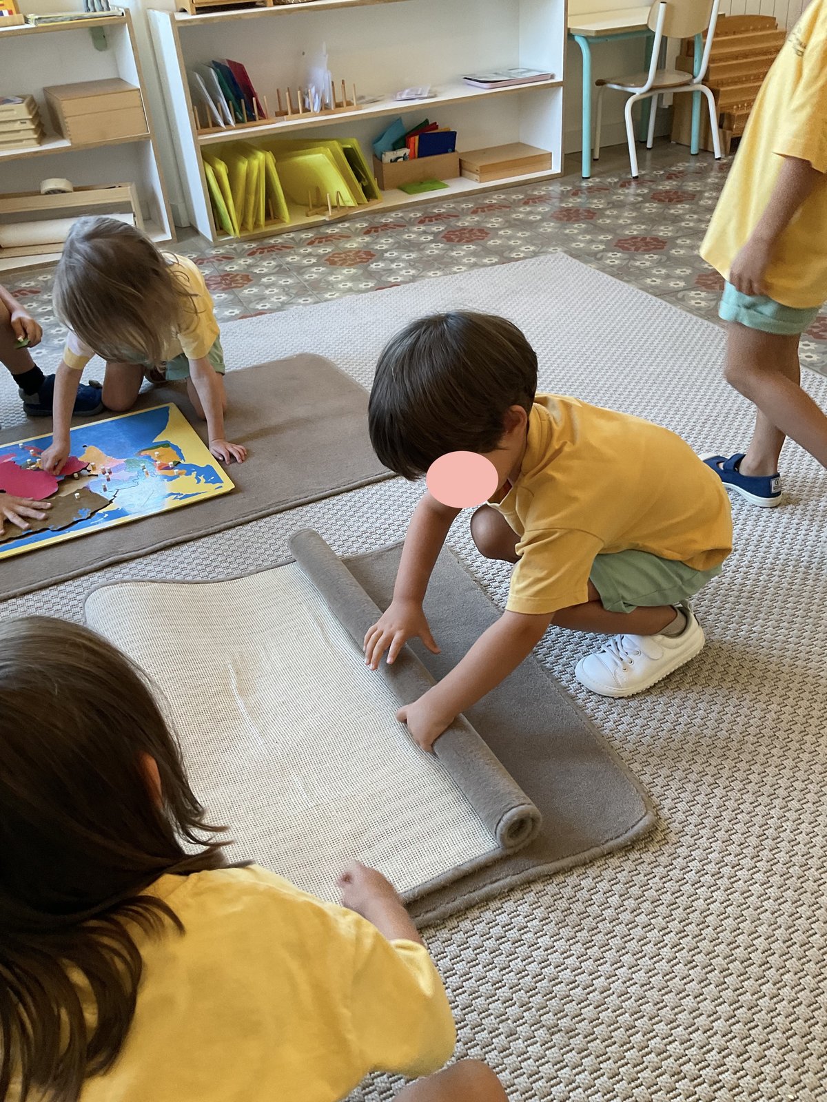 Un niño enrolla con cuidado una alfombra de trabajo en el aula