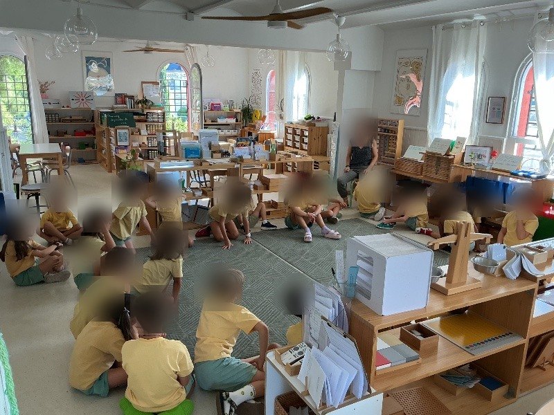 Des élèves d'Élémentaire assis ensemble par terre lors d'une réunion de classe avec leur guide