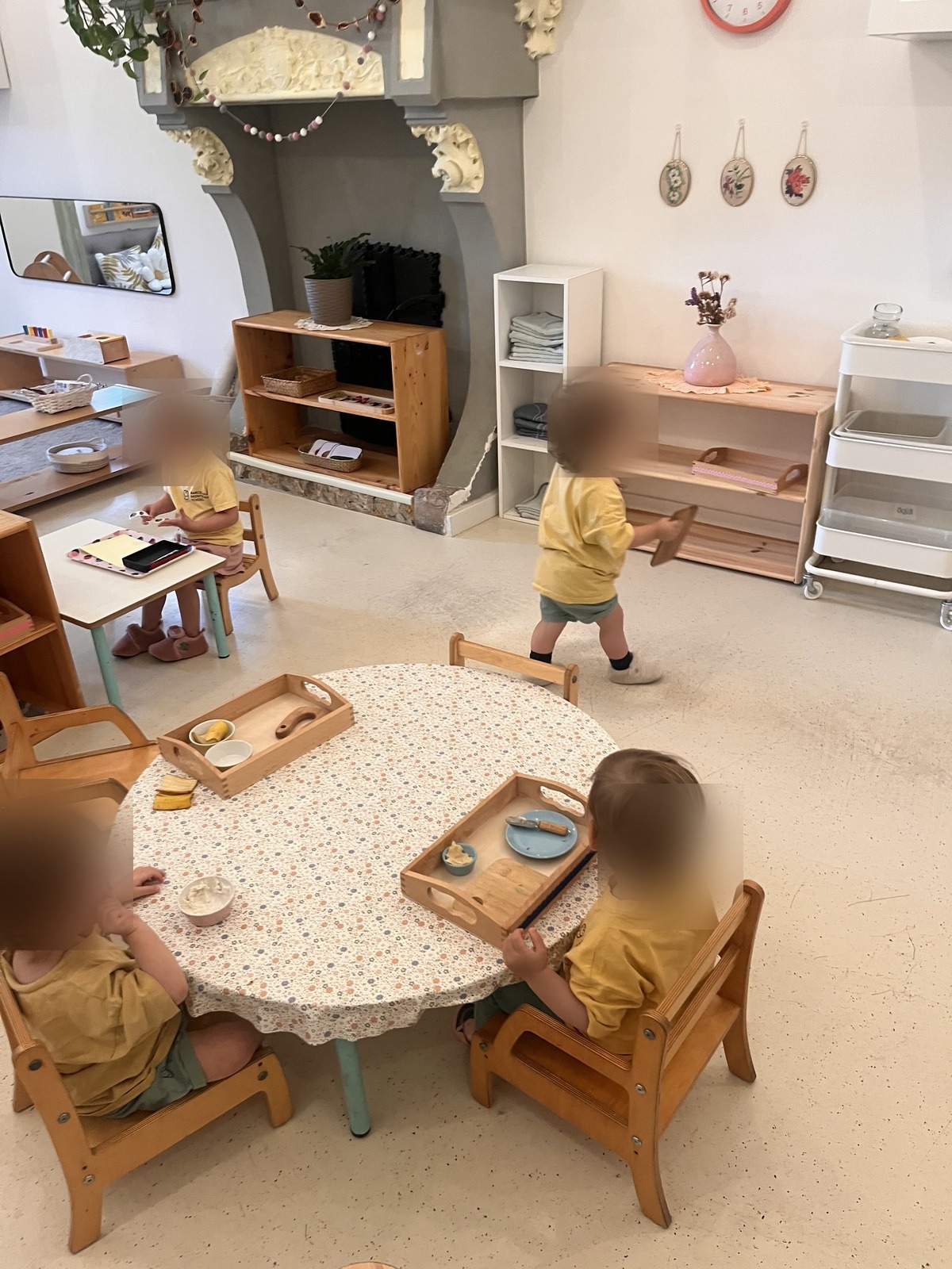 Un infant de Nido en una taula baixa amb una safata de preparació d'aliments, untant amb un ganivet petit