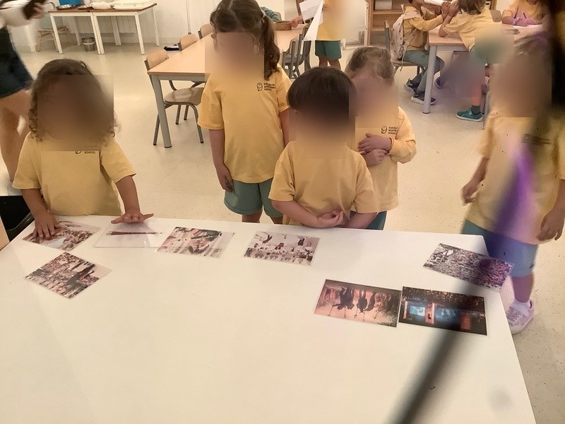 Niños y niñas observando fotografías de los espectáculos de la Mercè sobre una mesa