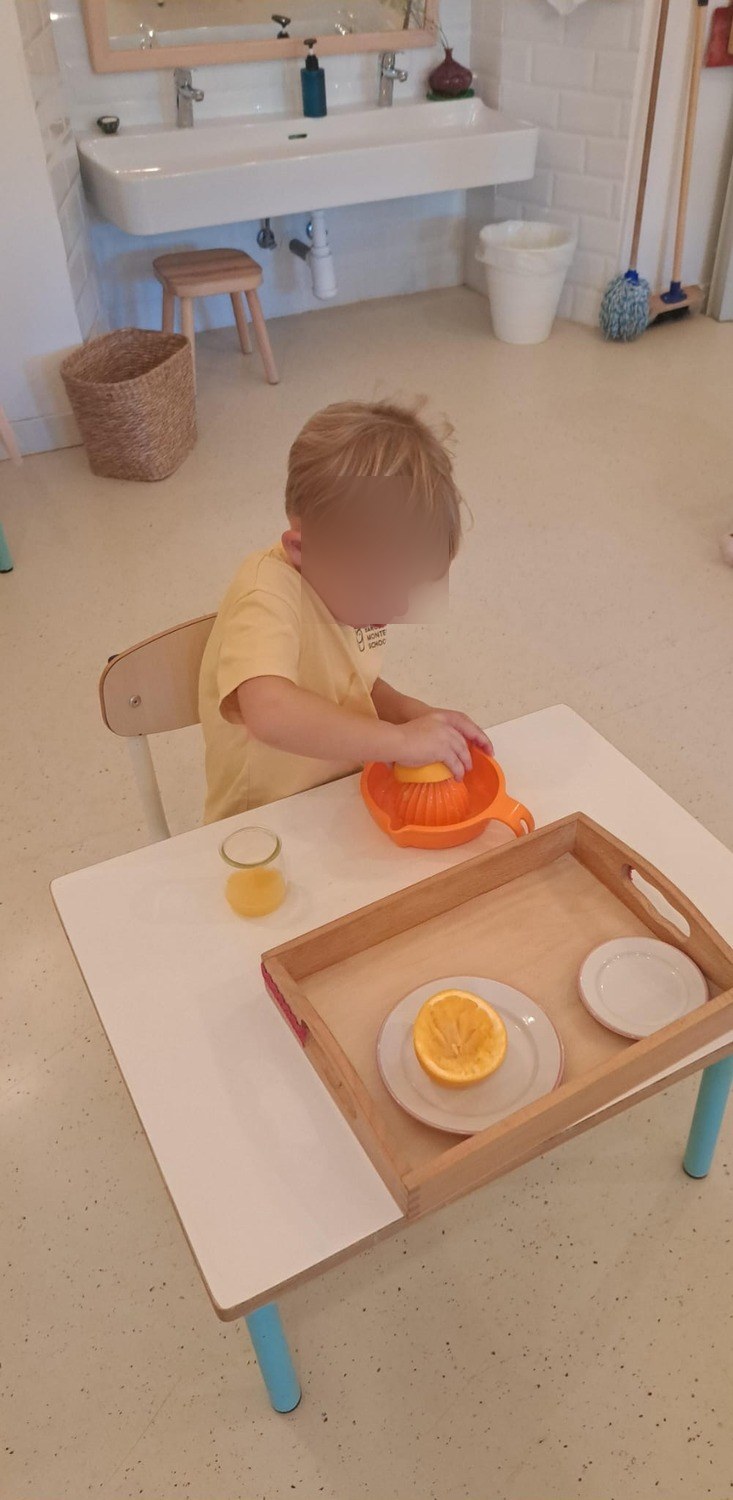 Un niño exprimiendo una naranja en la bandeja de preparación