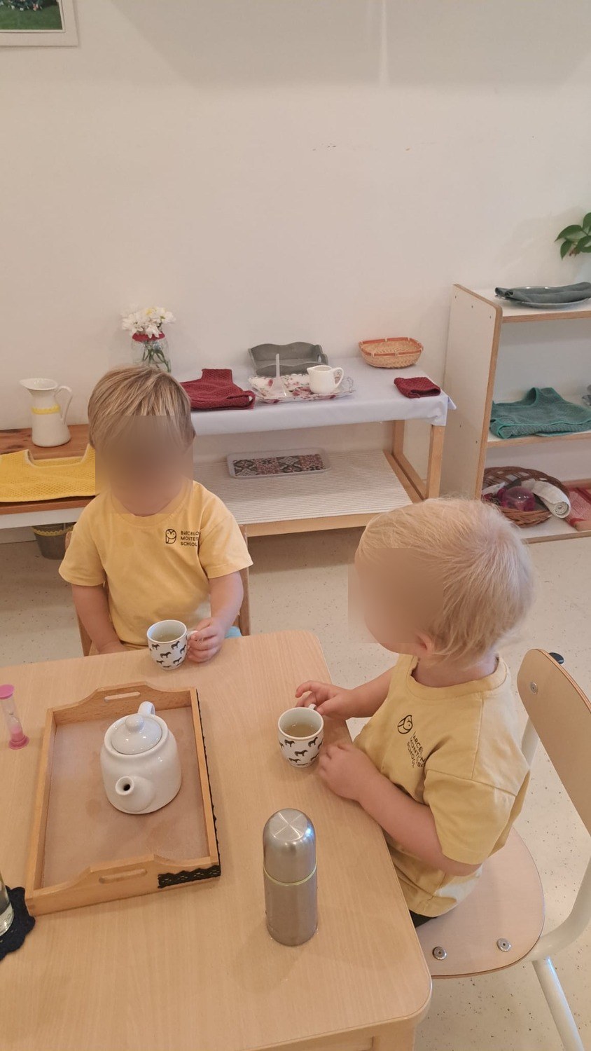 Dos niños compartiendo una tetera en una mesa pequeña