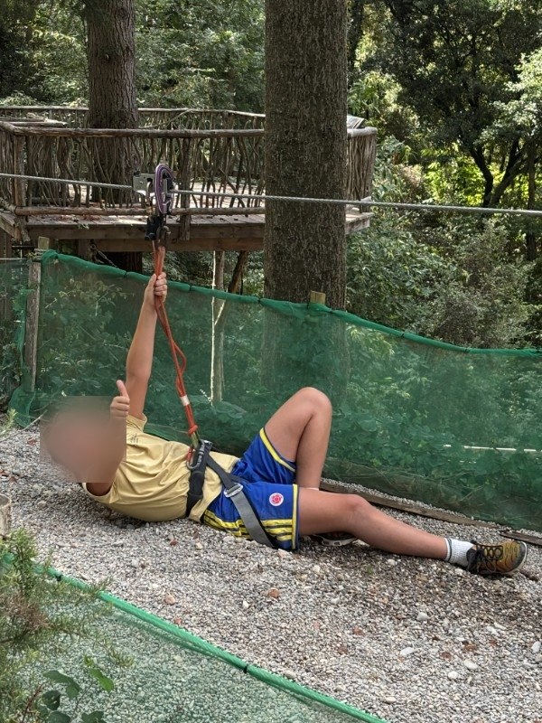 Un alumno en la tirolina de La Selva d'Aventures, levantando el pulgar