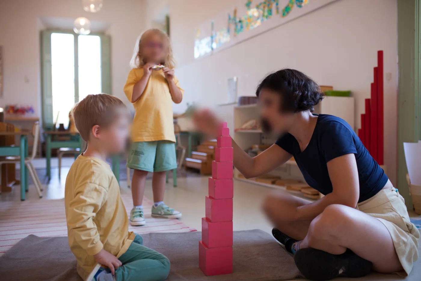 A guide presenting the pink tower to children in a Children’s House classroom at Barcelona Montessori School