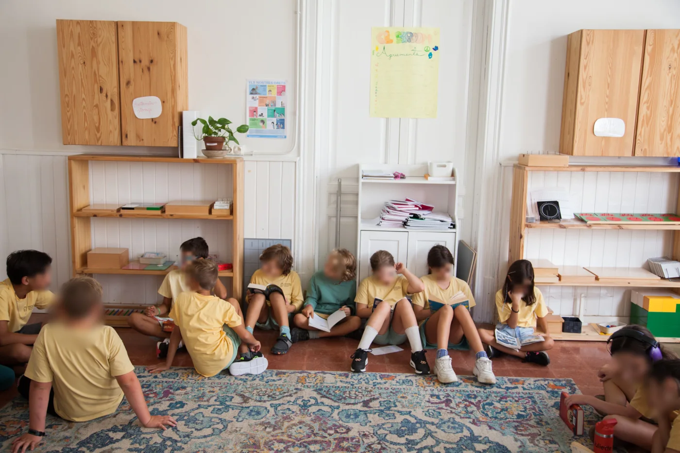 Niños leyendo juntos sobre la alfombra en Barcelona Montessori School