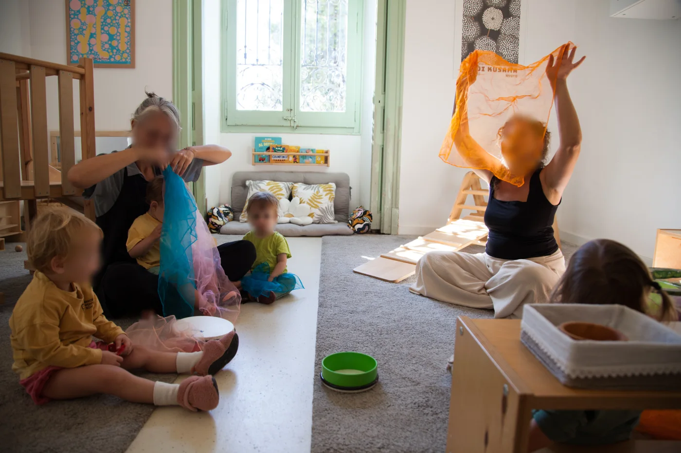 Niños pequeños y sus guías bailando con pañuelos de colores en Barcelona Montessori School