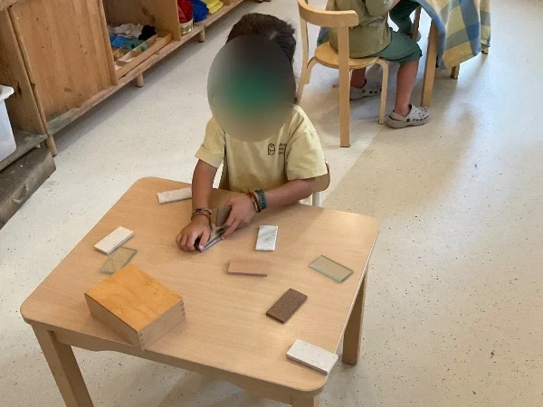 A Children’s House student exploring the touch tablets with their hands at Barcelona Montessori School