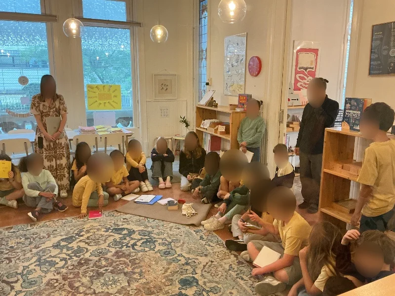 A primary class gathered on the rug for their community meeting at Barcelona Montessori School